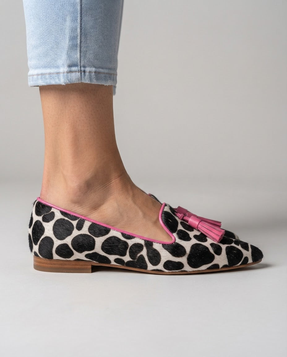Mocasín Ginebra — Elegante diseño en piel de vaca blanca y negra con borlas rosas
