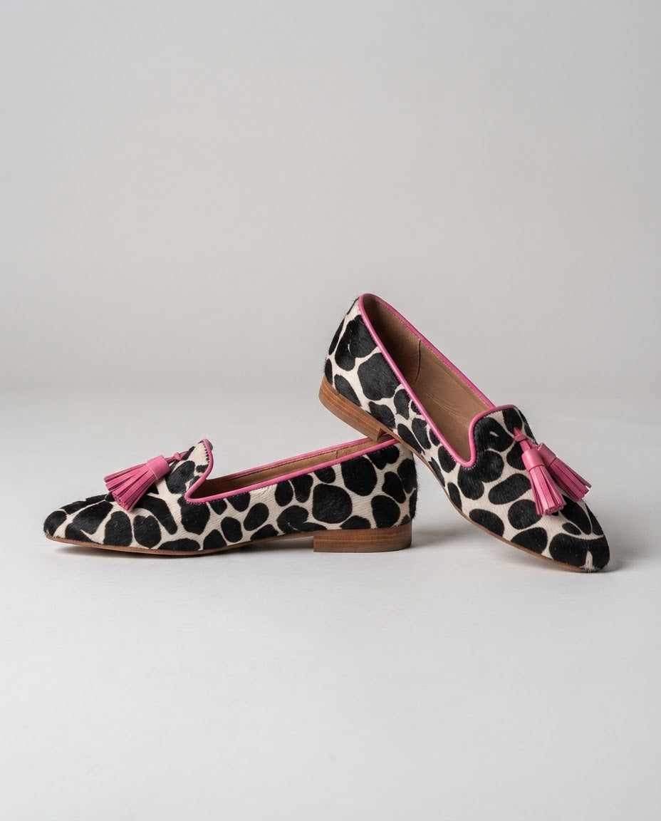 Mocasín Ginebra — Elegante diseño en piel de vaca blanca y negra con borlas rosas